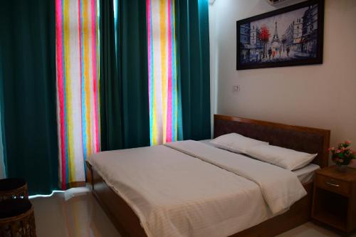 a bed in a bedroom with colorful curtains at River Stay - Homestay by Wanderlust Rural Tourism in Dehradun