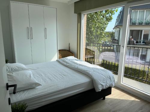 a bedroom with a bed and a large window at De Boei - Koksijde in Koksijde