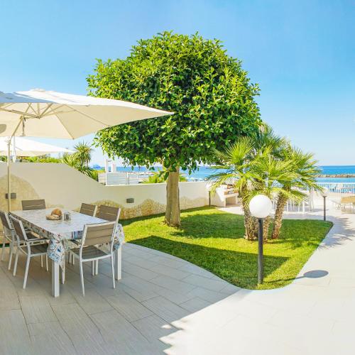 a patio with a table and chairs and an umbrella at Villa di Lusso sul Mare a Diamante - Villa Ventre in Belvedere Marittimo