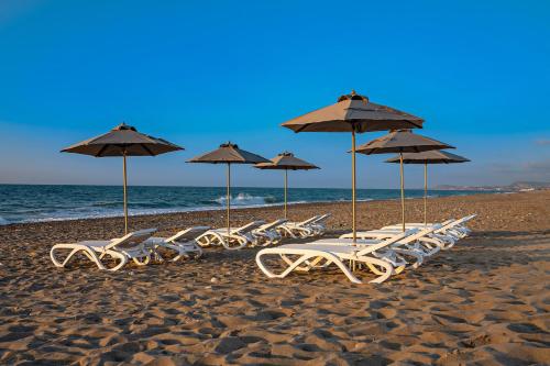 un groupe de chaises longues et de parasols sur une plage dans l'établissement Amara Villas, à Réthymnon