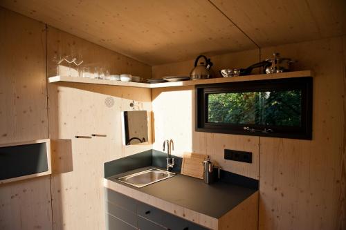 een kleine keuken met een wastafel en een raam bij Sleep Space 22 - Green Tiny Village Harz in Osterode