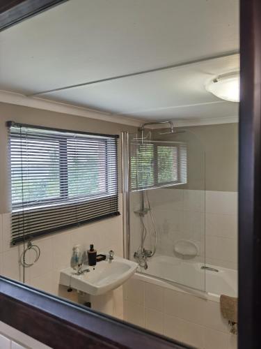 a bathroom with a sink and a tub and a mirror at Misty peaks Cloudlands in Bergview