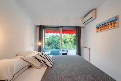 une chambre avec un lit et une grande fenêtre dans l'établissement Appartement 2 pièces au calme proche Martinez avec parking privé, à Cannes