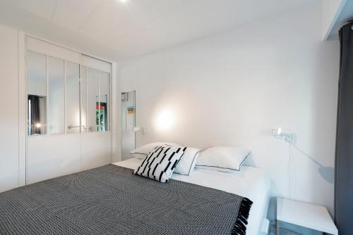 une chambre blanche avec un lit et un miroir dans l'établissement Appartement 2 pièces au calme proche Martinez avec parking privé, à Cannes
