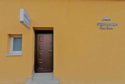 a yellow building with a door and a sign on it at Fernweh Haus Brasov in Braşov