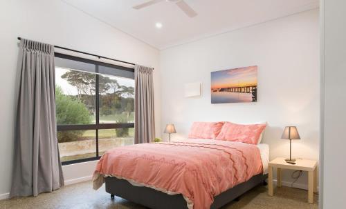 a bedroom with a bed and a large window at Jalilla Village in Kingscote