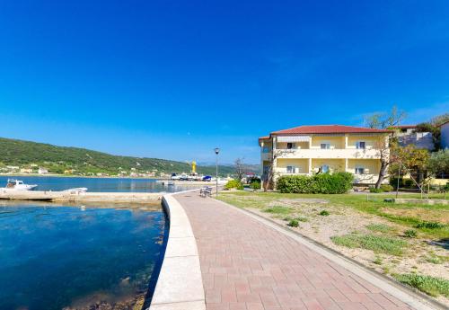 a walkway next to a body of water with a house at Apartments Darko by the sea in Supetarska Draga