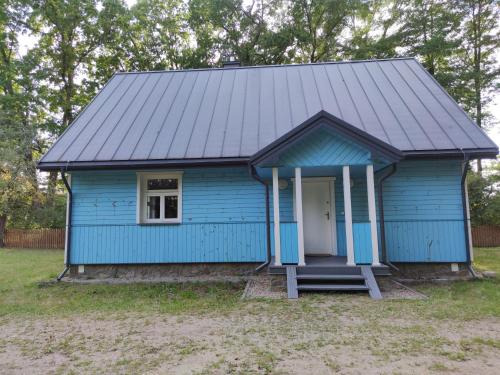 een blauwe schuur met een veranda en een deur bij Kraska Dom Wakacyjny w Sercu Puszczy Białowieskiej in Białowieża