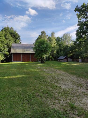 une grange dans un champ avec une grande cour dans l'établissement Kraska Dom Wakacyjny w Sercu Puszczy Białowieskiej, à Białowieża