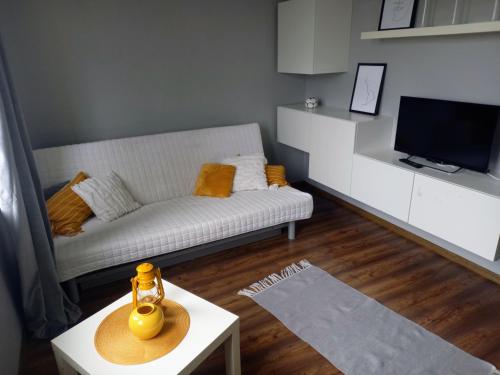 een woonkamer met een witte bank en een tafel bij Apartament 35 in Olsztynek