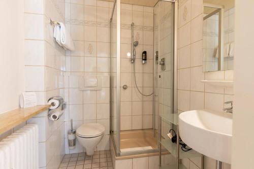 ein Bad mit einer Dusche, einem WC und einem Waschbecken in der Unterkunft Gästehaus Guggenberger in Höhenkirchen-Siegertsbrunn