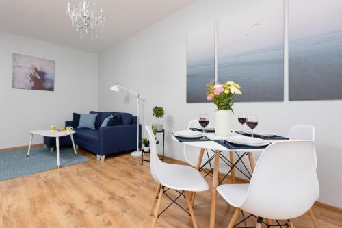 uma sala de estar com uma mesa e cadeiras e um sofá em Warsaw Bemowo Apartment with Balcony by Renters em Varsóvia