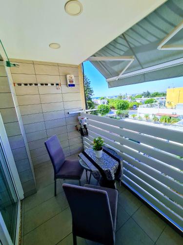 a balcony with purple chairs and a table with a plant at Hidden Lights Deluxe Apartment in Ayia Napa