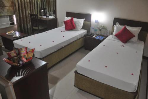 two beds in a hotel room with red pillows at The Presidency in Bhubaneshwar