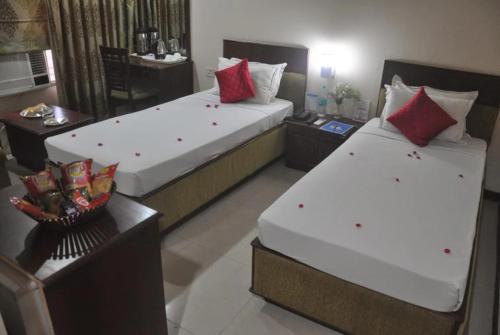 2 camas en una habitación de hotel con almohadas rojas en The Presidency, en Bhubaneshwar