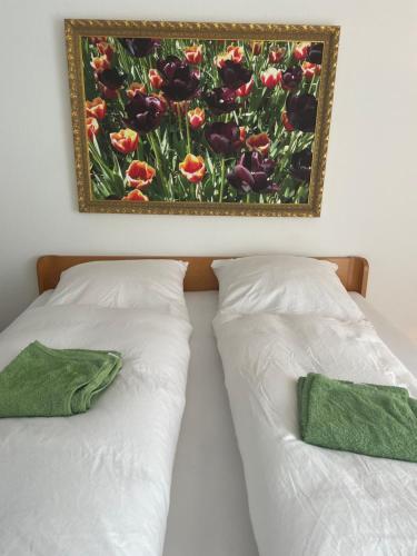 2 Betten mit weißer Bettwäsche und ein Gemälde an der Wand in der Unterkunft Doppelzimmer in Borgholzhausen