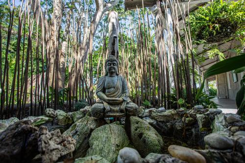 a statue sitting on a pile of rocks in front of trees at Namaste Beach Club & Hotel in Tierra Bomba