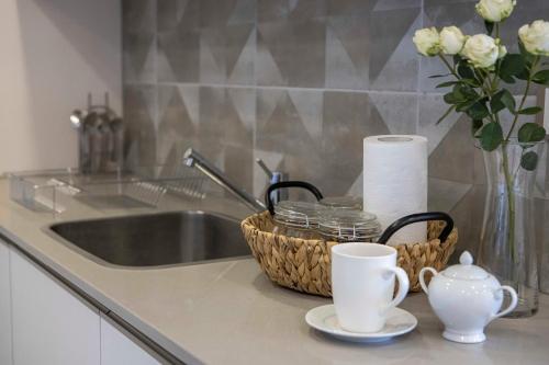 a kitchen counter with a sink and a basket of cups at The Skies by YourHost, Westlands Nairobi in Nairobi