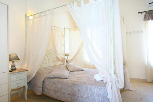 a bedroom with a canopy bed with white curtains at On The Beach Apartments in Hora Sfakion