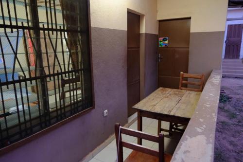 Habitación con mesa de madera, sillas y ventana. en Studio tout équipé au sein de l'ONG Okouabo, en Parakou