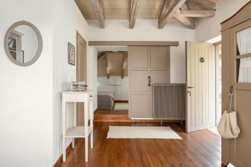 um corredor com paredes brancas, pisos em madeira e um espelho em Avragonio em Papigko