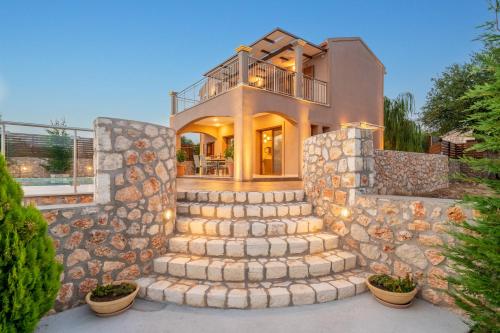 a home with a stone wall and stairs at Villa Cleopatra Fiskardo in Fiskardho