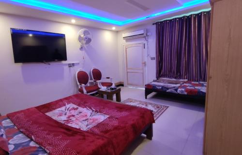 a room with a bed and a tv on the wall at Sunrise Rest House in Islamabad
