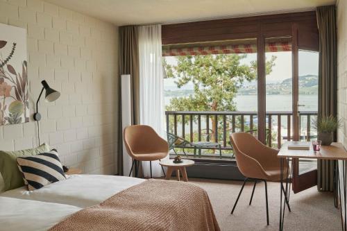 a bedroom with a bed and a balcony at Hotel Bad Murtensee in Murten