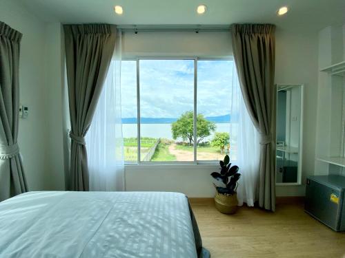 a bedroom with a large window with a view of the ocean at PB Place @ Kwan Payao in Phayao