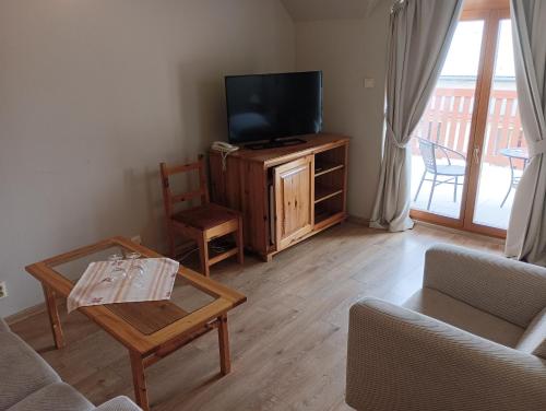 a living room with a tv and a couch and a table at Penzión Réva in Turna nad Bodvou