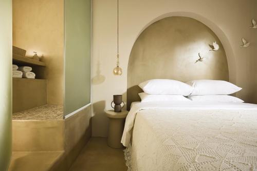 a bedroom with a bed with an arched headboard at Elaia Luxury Suites Mykonos in Mýkonos City
