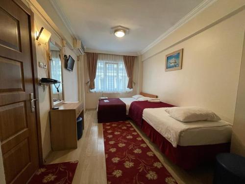 イスタンブールにあるアモーレ ホテル イスタンブールのベッド2台と赤い敷物が備わるホテルルームです。