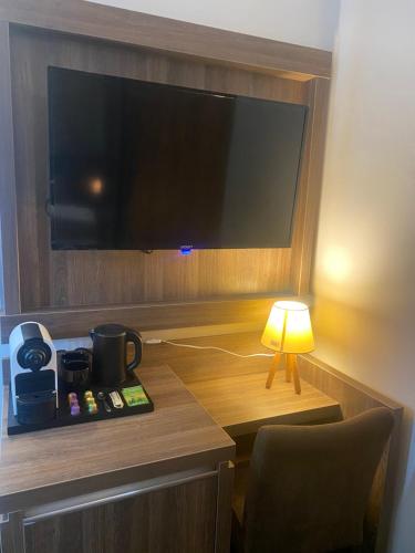 a room with a flat screen tv and a lamp at Hotel Cataleya in Almere