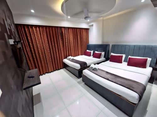 two beds in a room with red curtains at Hotel City Heart Shirdi in Shirdi