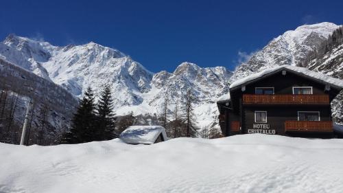 a snow covered building in front of a mountain at Hotel Cristallo in Macugnaga