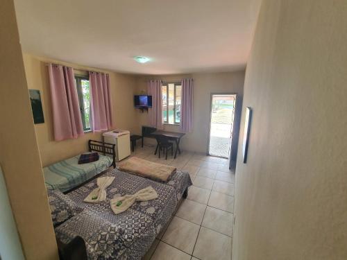 uma sala de estar com duas camas e uma mesa em Espaço La Gondola em Araruama
