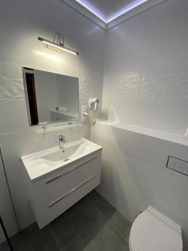 a white bathroom with a sink and a toilet at City Apartment Getta in Krakow