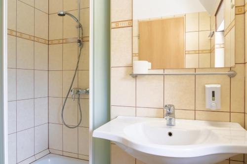La salle de bains est pourvue d'un lavabo et d'une douche. dans l'établissement BALATONAIR Vendégház, à Balatonfüred