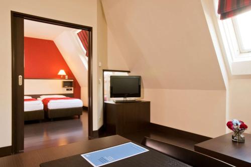 a hotel room with a bed and a television at NH Wien City in Vienna