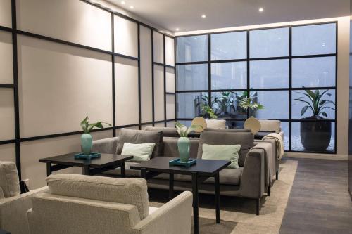 a waiting room with couches and tables and windows at NH Collection Buenos Aires Crillón in Buenos Aires