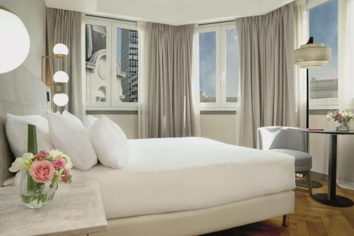 a white bedroom with a large bed and a table at NH Collection Buenos Aires Crillón in Buenos Aires