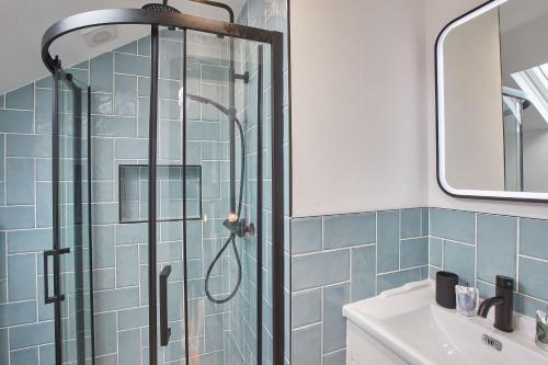 a bathroom with a shower with blue tiles at Grumbles Cottage at Loggerhead Yard in Whitby