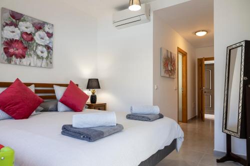 a bedroom with a white bed with red and blue pillows at Ideal for family holidays, near beach and golf- Casa James in La Guirra