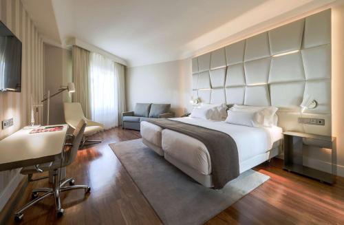 a hotel room with a large bed and a desk at NH Collection Madrid Colón in Madrid