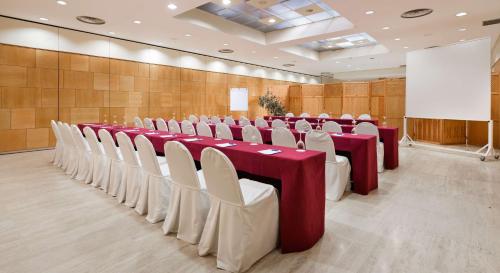 a conference room with red and white tables and chairs at NH Ciudad Real in Ciudad Real