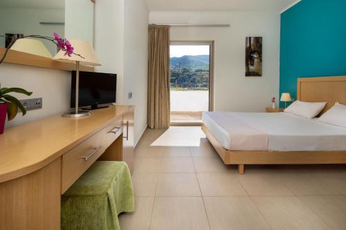 a bedroom with a bed and a desk with a television at Elena Beach Hotel in Kissamos