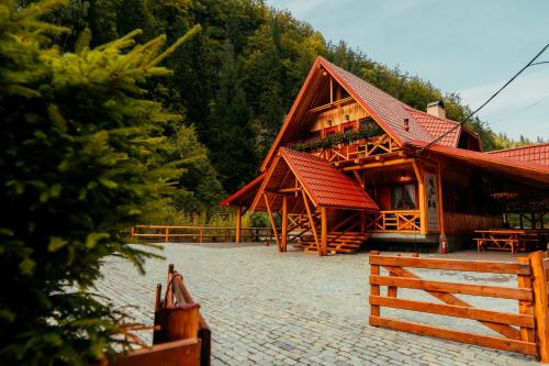 a building with a red roof and a fence at Casa Cheile Dâmbovicioarei - Cabana 1 in Dîmbovicioara