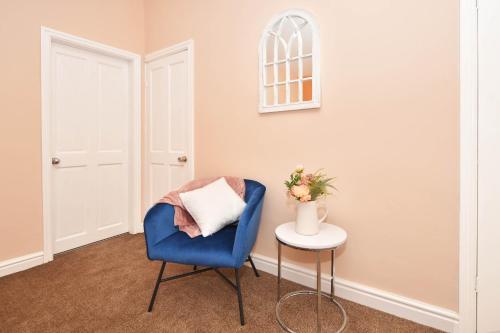 una sedia blu seduta in una stanza con tavolo di All Saints House by YourStays a Stoke on Trent