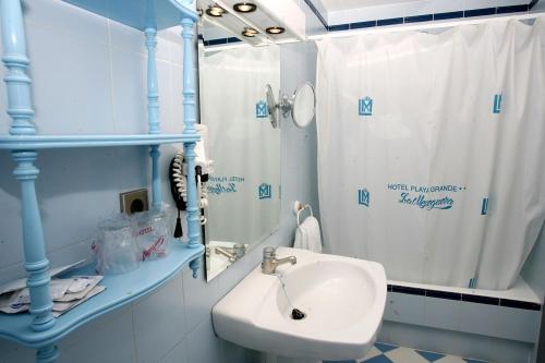 a blue and white bathroom with a sink and a shower at Hotel Playa Grande in Puerto de Mazarrón