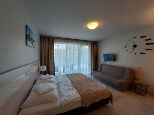 a bedroom with a bed and a couch and a clock at Apartament Czarna Góra ISCHGL 18 in Sienna